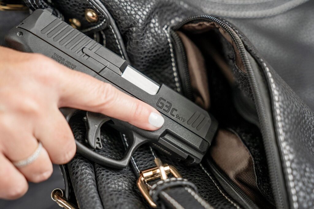 woman drawing a handgun from a purse. Specifically a Taurus G3C